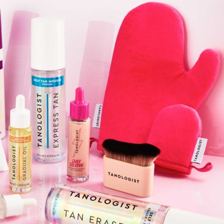 Tanologist self-tanning product lineup on pink background, including Gradual Oil, Express Tan mousse, Day Glow drops, Tan Eraser, and a pink tanning mitt with application brush.