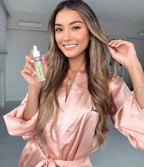 Model holding bottle of dark self tanning mousse