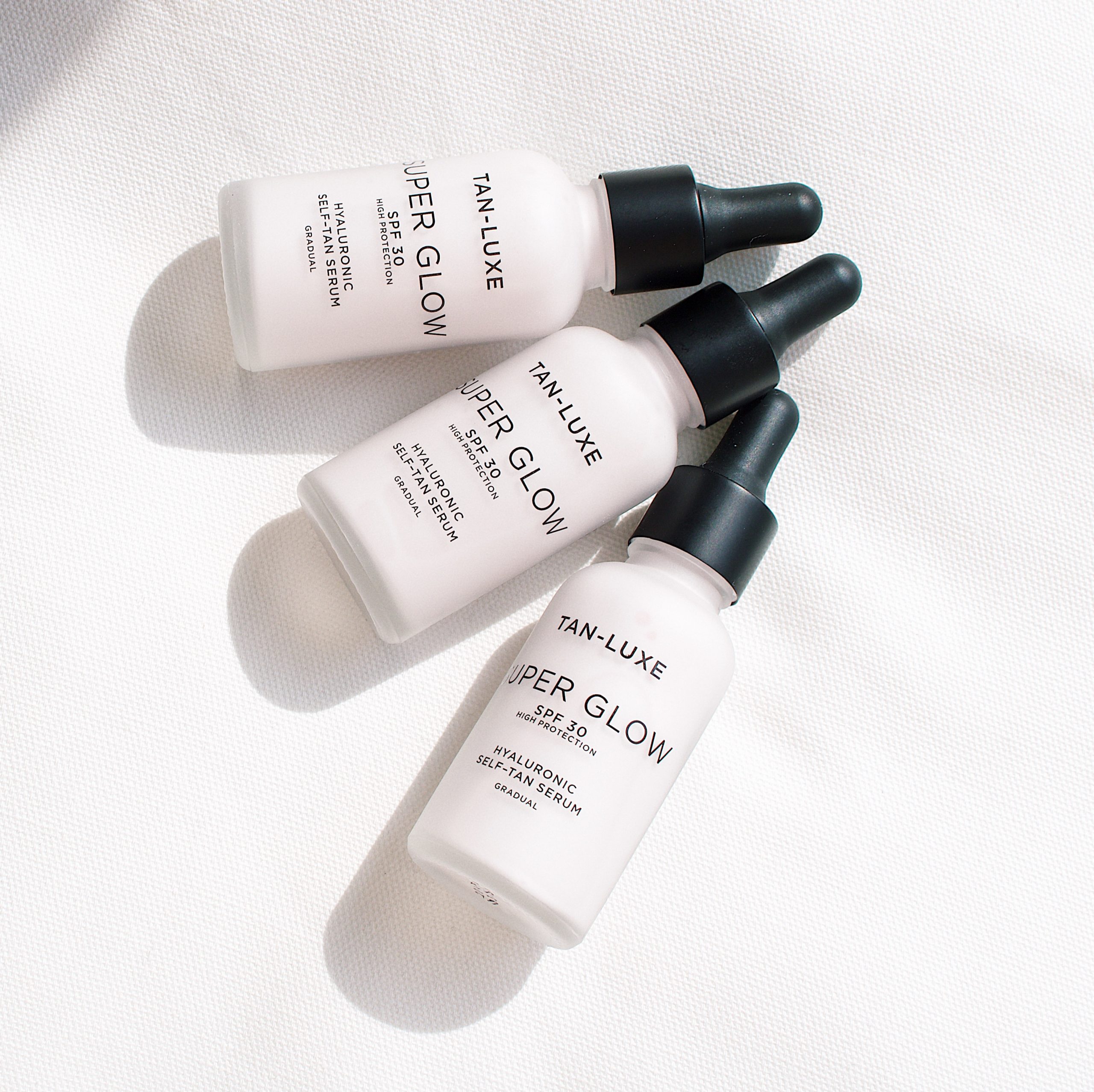 Three bottles of Tan Luxe Super Glow SPF 30