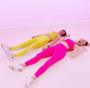 Two laughing girls in athletic clothing lying on ground